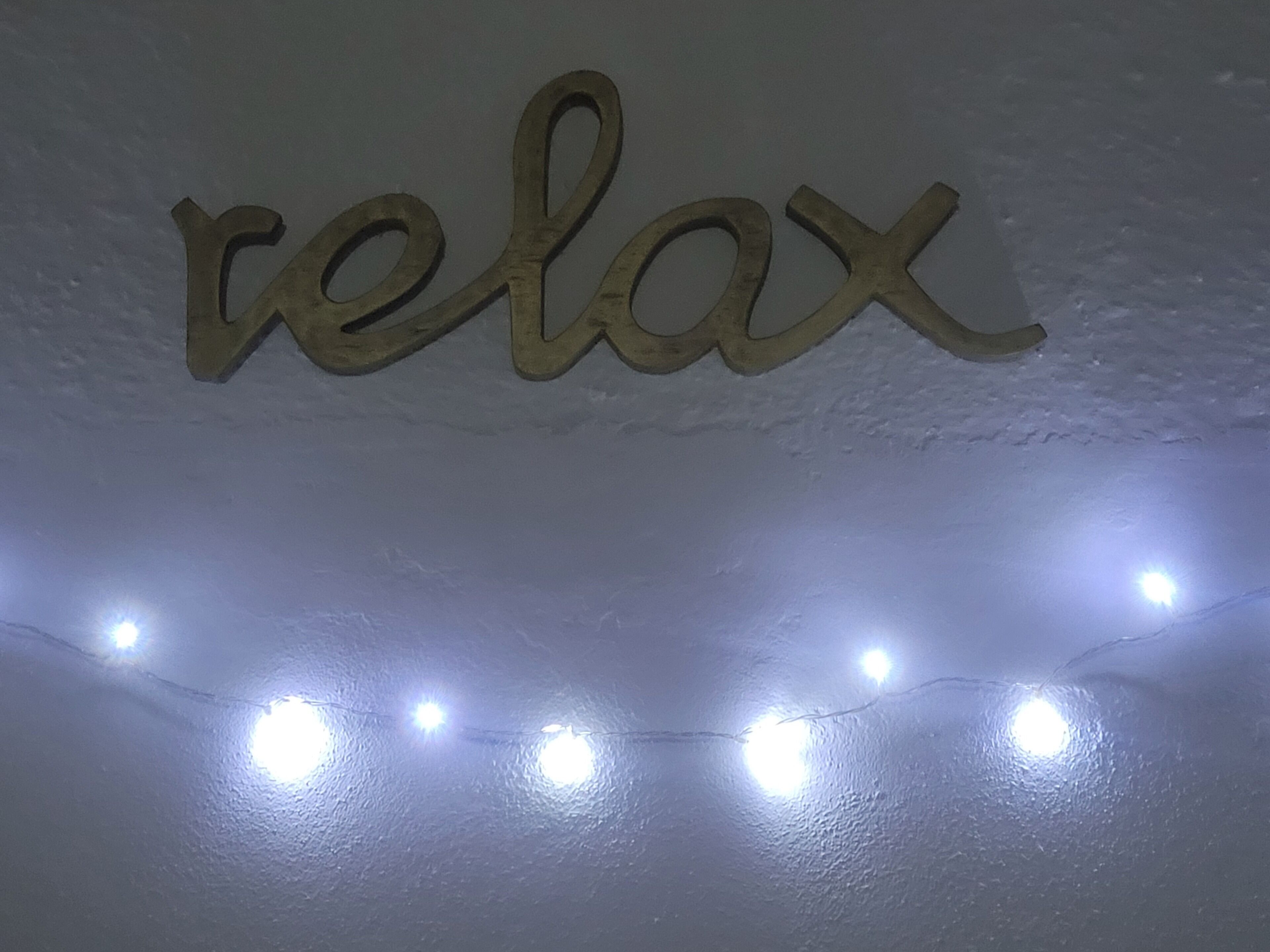 A wall with the word "relax" and a string of lights.