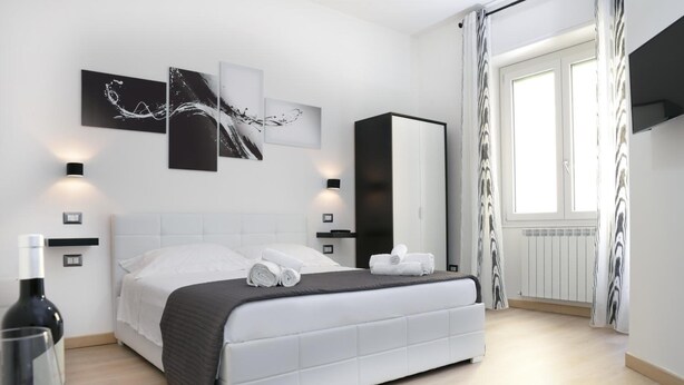 A modern bedroom with a large bed, bedside tables, a wardrobe, and abstract wall art.