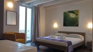 A hotel room with a bed, a chair, a table, and a large window with curtains. - Up Room & Suite (Lecce)