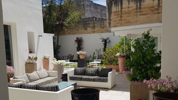 A sunlit outdoor seating area with wicker furniture and potted plants. - Up Room & Suite (Lecce)