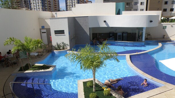 A rooftop swimming pool with a modern design, surrounded by lounge chairs and small palm trees. - Atrium - Achei Ferias (Caldas Novas)