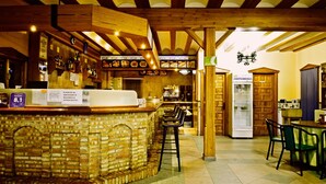 A bar area with a brick counter, wooden beams, and a refrigerator.
