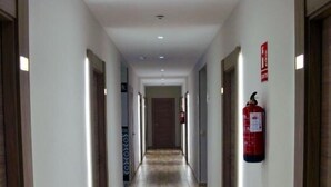 A long, narrow hallway with wooden flooring and white walls.