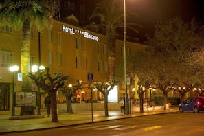 Un hotel llamado "HOTEL *** Biokovo" con un letrero, un cartel de estacionamiento y árboles a lo largo de la acera.