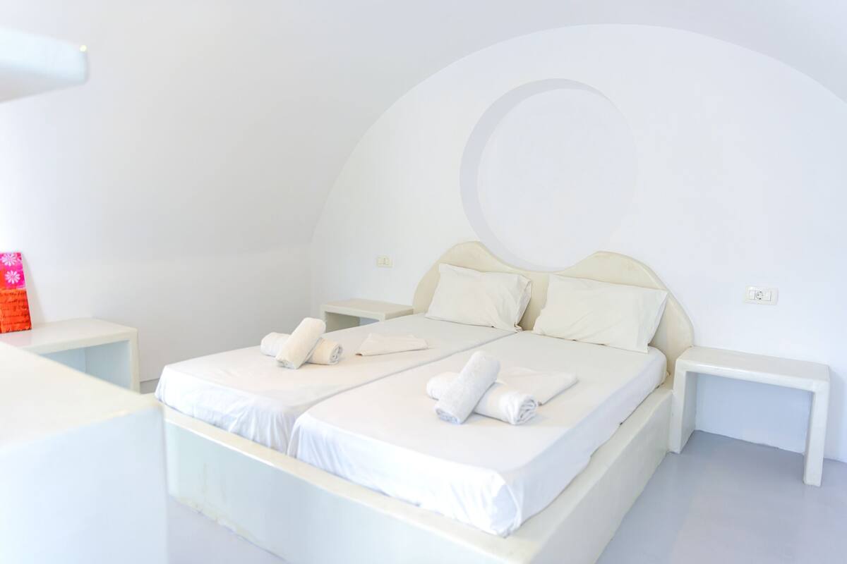 A minimalist bedroom with a large bed, two bedside tables, and a curved wall design.