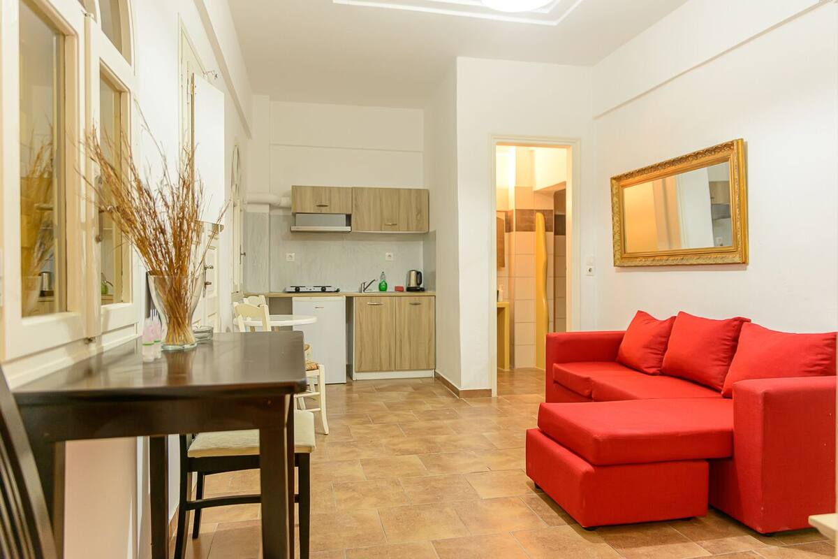 A compact living space with a kitchenette, a dining area, and a red sofa.