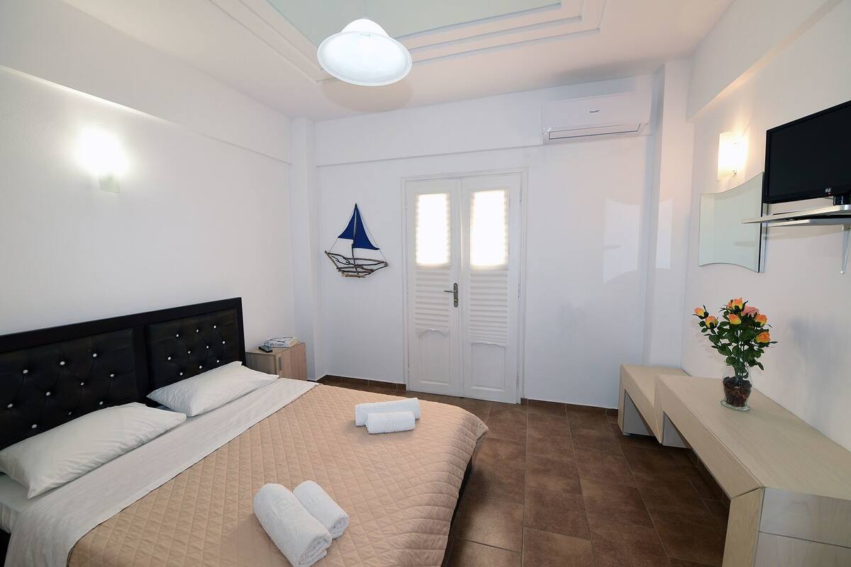 A hotel room with a bed, bedside table, and a TV.