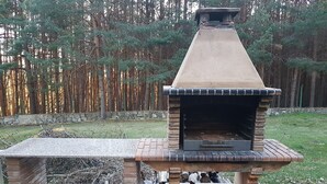 A brick-built outdoor oven with a chimney, surrounded by a stone wall and a grassy area. - La Vista de Gredos (Navarredonda de Gredos)