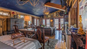 A spacious room with a large bed, a wooden desk, and a chandelier.