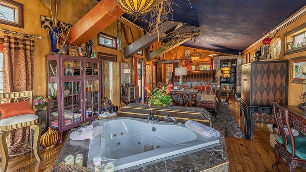 A luxurious bathroom with a large bathtub, wooden flooring, and a variety of decorative items.