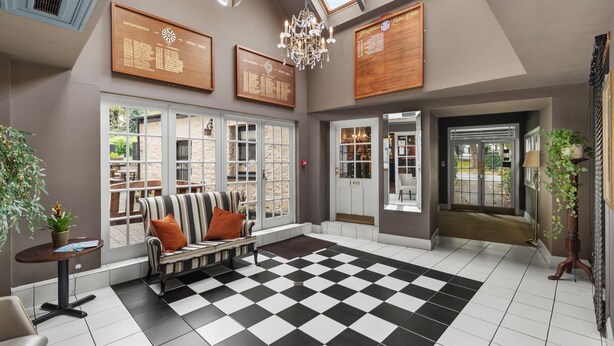 A spacious room with a checkered floor, a striped sofa, and a chandelier. - Hotel Mariners (Haverfordwest)