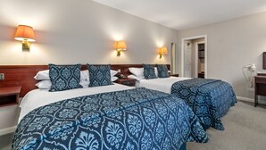 A hotel room with two beds, each with a blue patterned bedspread, two wall-mounted lamps, and a wooden headboard. - Hotel Mariners (Haverfordwest)
