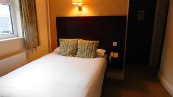Una camera d'albergo con un letto, una lampada da comodino, un telefono e una porta che dà su un'altra stanza.