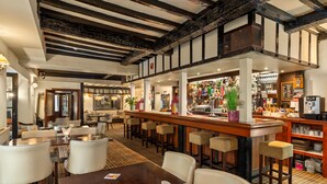 A bar area with stools, a wooden bar counter, and a variety of bottles and glasses. - Hotel Mariners (Haverfordwest)