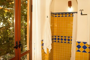 A bathroom with yellow and blue tiles, a white towel hanging on a rack, and a window with a view of trees.
