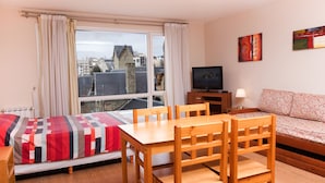 A room with a bed, a wooden table with chairs, a TV, and a sofa. - Civico Apartments (San Carlos de Bariloche)
