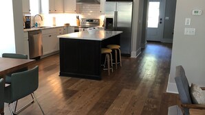 Une cuisine moderne dotée d’un îlot central, d’appareils électroménagers en acier inoxydable et d’un revêtement de sol en bois.