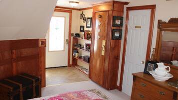 A room with a wooden cabinet, a white door, and a dresser with a white pitcher and bowl.