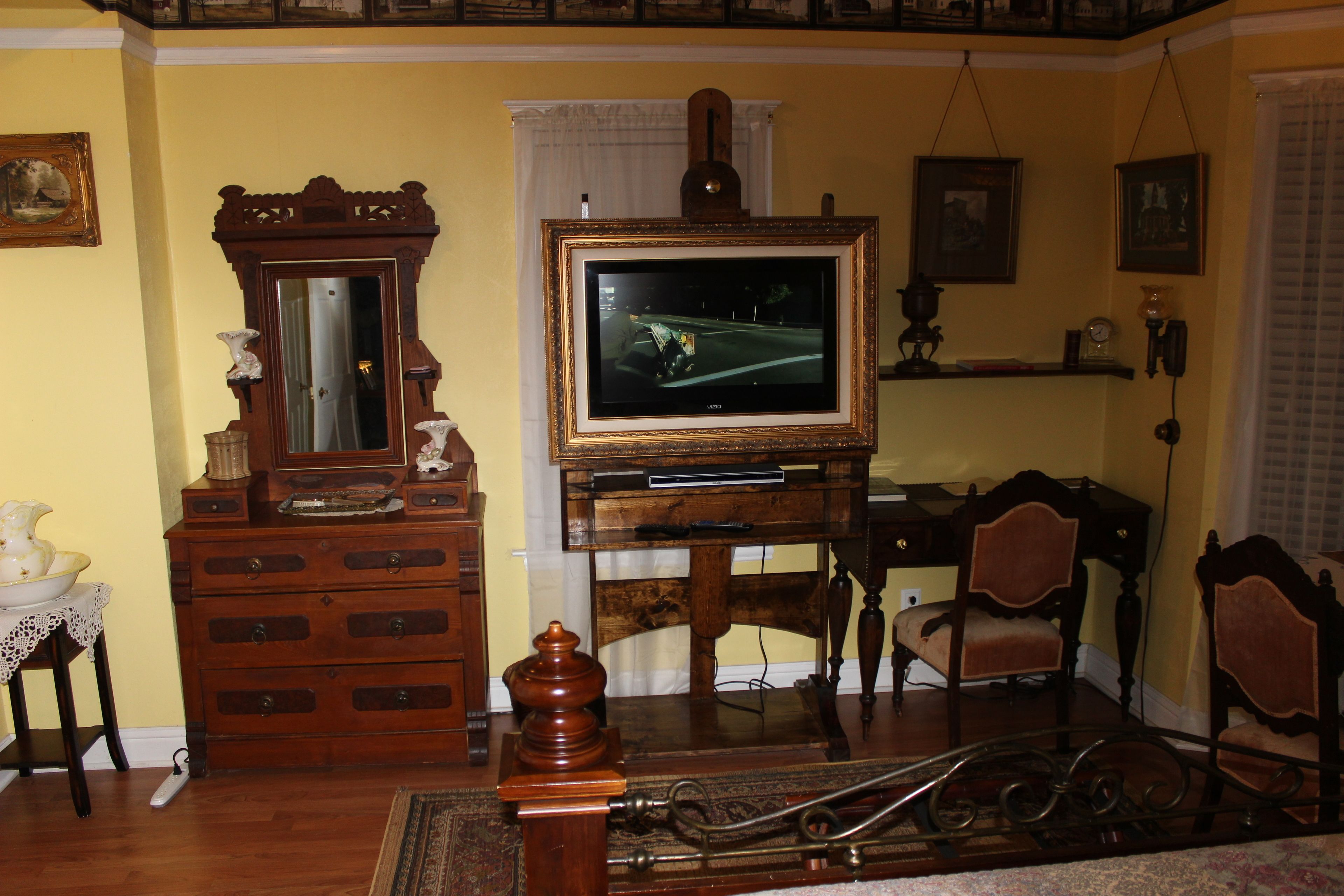 Un salón tradicional con un mueble bajo para la televisión de madera, un teléfono rotativo antiguo y muebles clásicos.