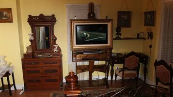 Un salón tradicional con un mueble bajo para la televisión de madera, un teléfono rotativo antiguo y muebles clásicos.