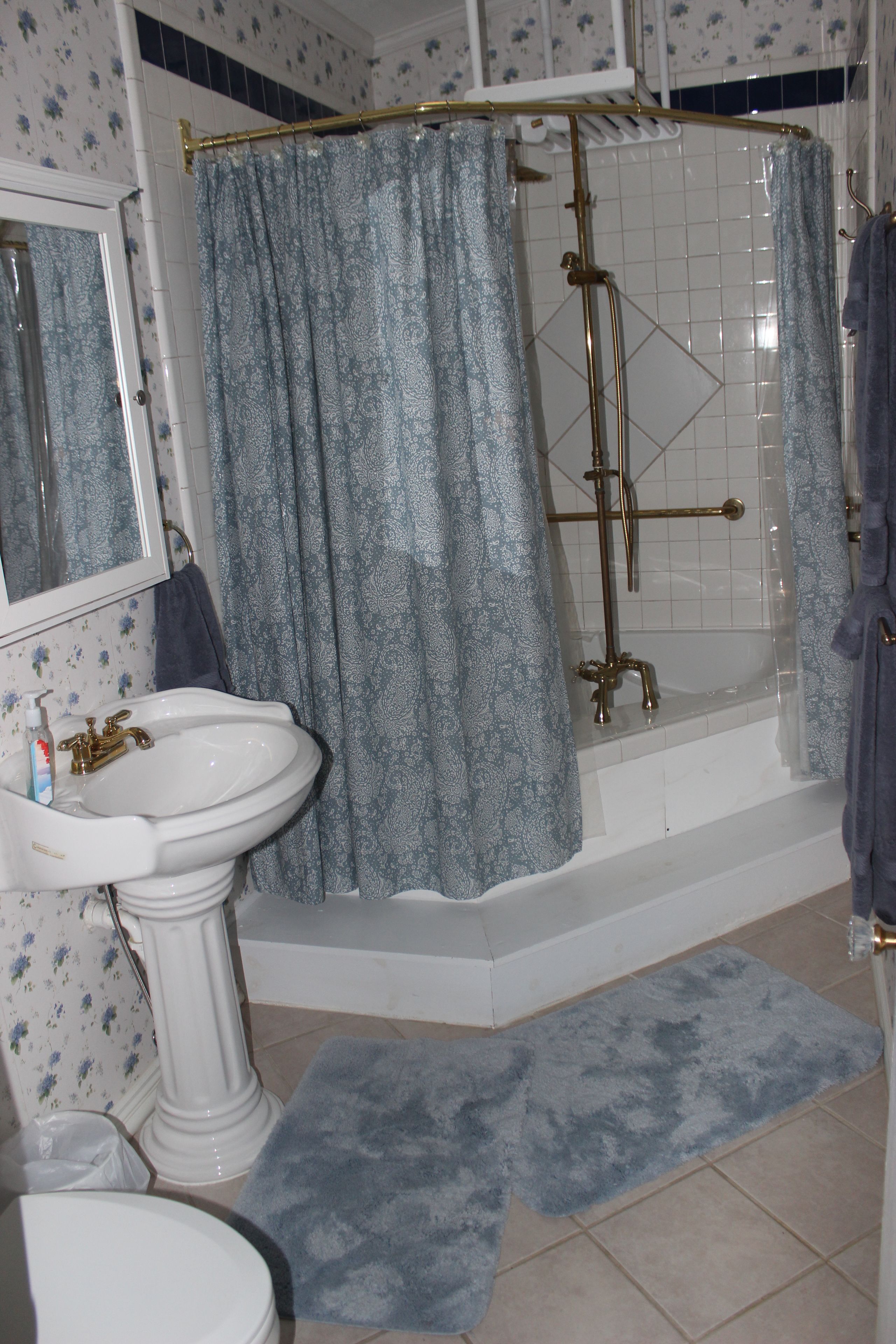Une salle de bain avec un lavabo sur colonne, une baignoire et une douche.