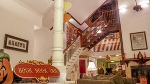 A cozy living room with a fireplace, a staircase, and a sign reading "BOOK NOOK INN". - Book Nook Inn (Lumberton)