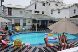 A pool area with colorful chairs, a pool, and a building in the background.