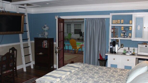 A bedroom with a bed, a dresser, a desk with a microwave, and a chair. - Book Nook Inn (Lumberton)