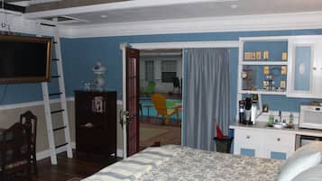 Un dormitorio con cama, cómoda, escritorio con microondas y silla.