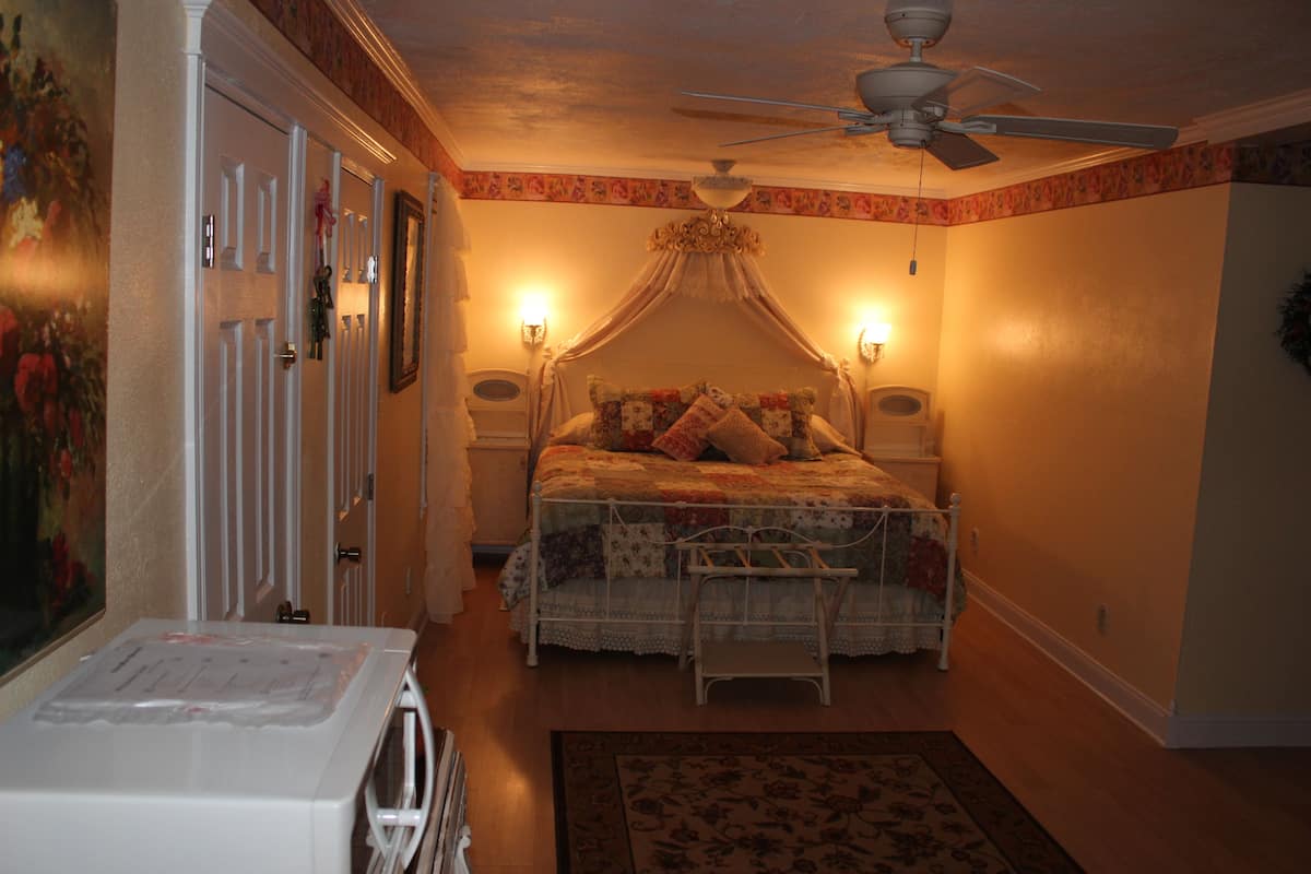 A bedroom with a canopy bed, a ceiling fan, and two bedside lamps.