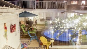 A covered outdoor patio with a pool, wooden deck, and seating area with chairs and a table. - Book Nook Inn (Lumberton)
