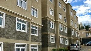 A multi-story residential building with a brick facade, multiple windows, and a paved driveway. - Milimani Serviced Apartments (Nakuru)