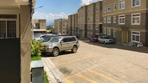 A multi-story residential building with a parking area in front. - Milimani Serviced Apartments (Nakuru)