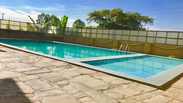 A rectangular swimming pool with clear blue water, surrounded by a stone-tiled deck. - Milimani Serviced Apartments (Nakuru)