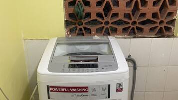 A washing machine with a digital display and multiple buttons, located in a room with a tiled floor and a decorative wall panel.