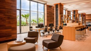 A modern office space with a large desk area, comfortable seating, and a view of palm trees. - Fiesta Inn Tuxtla Fashion Mall (Tuxtla Gutierrez)