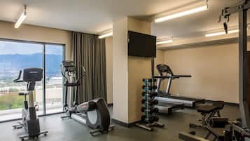 A gym with cardio equipment, a treadmill, and a weight rack.