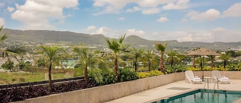 A rooftop pool with a view of a cityscape and mountains.
