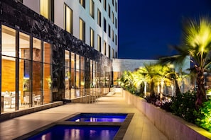 Un hotel moderno con piscina, zona de estar exterior y ventanas bien iluminadas.