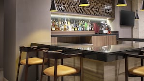 Un área de bar moderna con techo de madera, taburetes negros y una barra bien surtida.