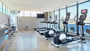 A modern gym with treadmills, dumbbells, and a large window offering a view of the sky. - Fairfield Inn & Suites Aguascalientes (Aguascalientes)