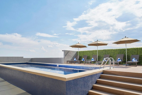 Alberca al aire libre, sombrillas en la alberca y camastros
