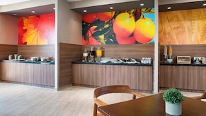 A modern kitchen with wooden cabinets, a black countertop, and a large fruit mural on the wall. - Fairfield Inn & Suites Aguascalientes (Aguascalientes)
