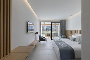Una habitación de hotel moderna con una cama grande, un escritorio y vistas al exterior.