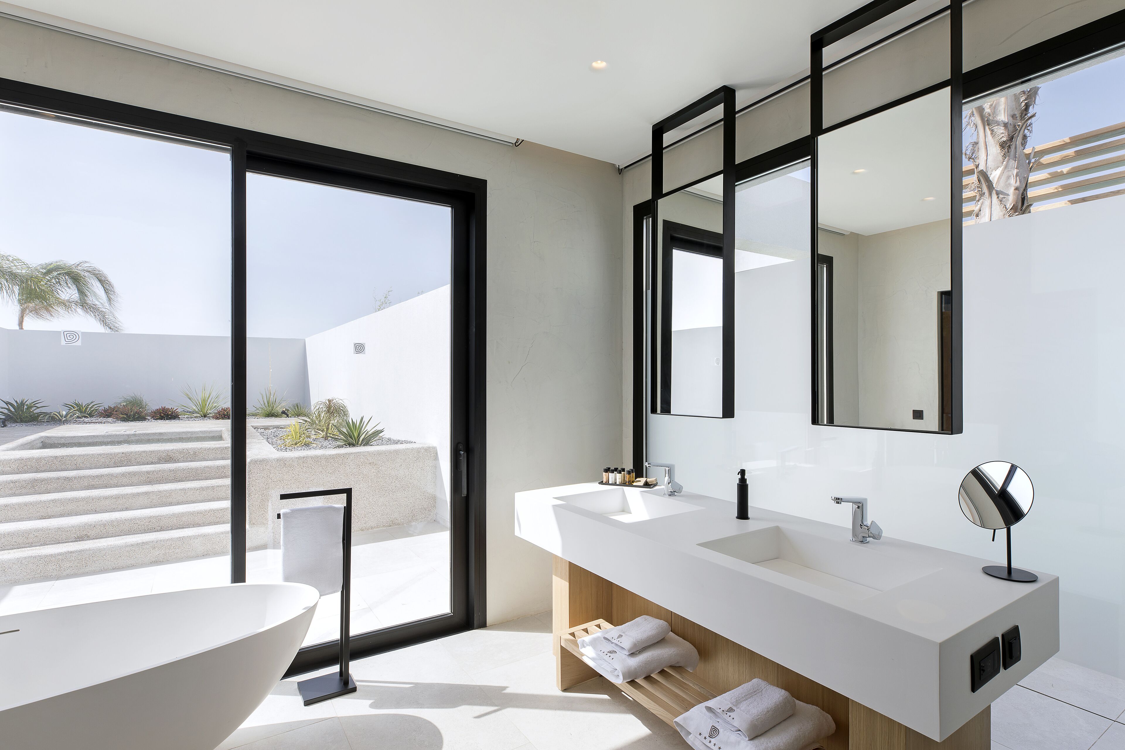 Een moderne badkamer met een groot bad, twee wastafels en een grote spiegel.