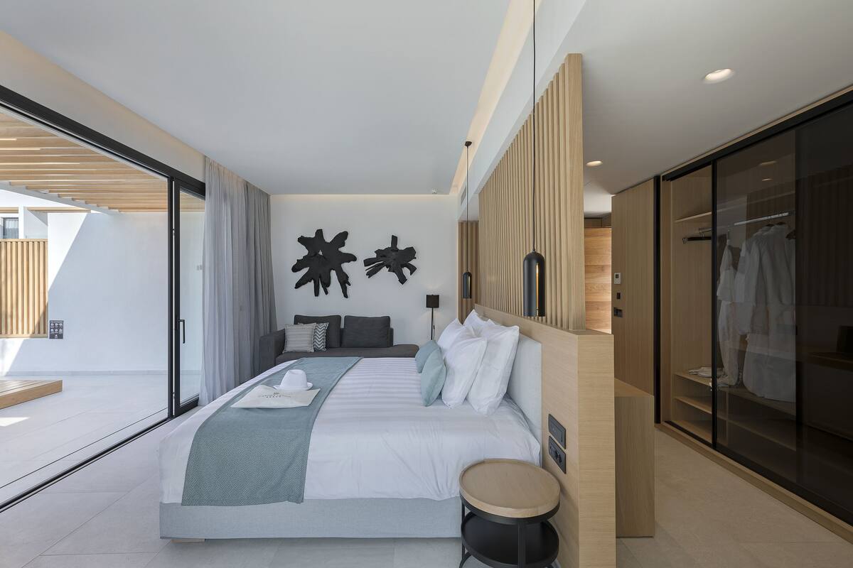 A modern bedroom with a large bed, a bedside table, and a wardrobe.