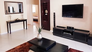 A modern living room with a TV, a console table, a sofa, and a coffee table. - Luxurious Apartment in Century City (Cape Town)