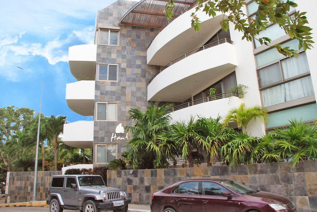A multi-story hotel with a modern design, featuring balconies and a stone facade.