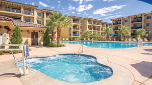Un hotel con piscina, palme e un cielo azzurro limpido.