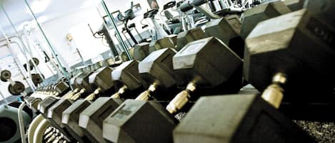 A gym with rows of dumbbells and exercise equipment.